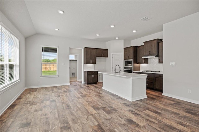240 Camino Verde Dr, San Marcos, TX 78666 - kitchen featuring stainless steel appliances, wood finished floors, dark brown cabinets, light countertops, and backsplash