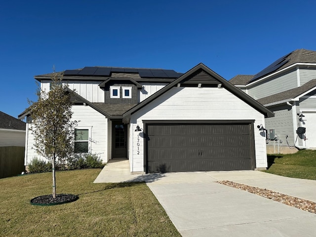 17012 Wind Chime Dr, Manor, TX 78653 - view of front of property featuring driveway, solar panels, a garage, a front lawn, and board and batten siding