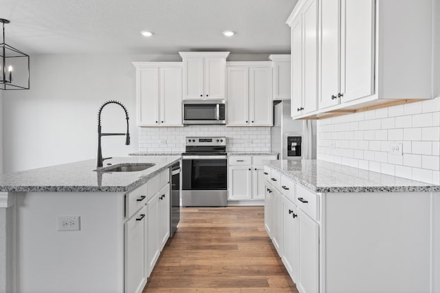 17012 Wind Chime Dr, Manor, TX 78653 - kitchen with appliances with stainless steel finishes, a sink, white cabinets, light stone countertops, and recessed lighting