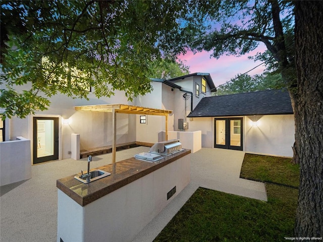 2004 N Cuernavaca Dr, Austin, TX 78733 - back of property at dusk featuring area for grilling, french doors, stucco siding, a patio area, and a sink
