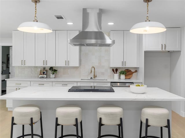 2004 N Cuernavaca Dr, Austin, TX 78733 - kitchen featuring wall chimney range hood, backsplash, light wood-style floors, white cabinets, and a kitchen breakfast bar