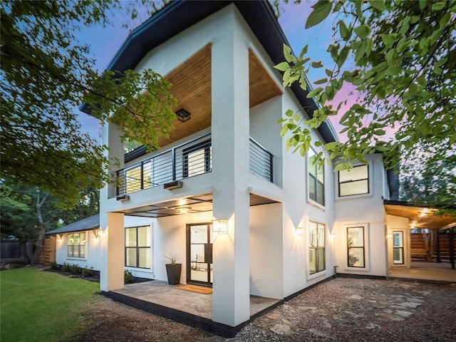 2004 N Cuernavaca Dr, Austin, TX 78733 - rear view of house with stucco siding, a balcony, a patio area, and a yard
