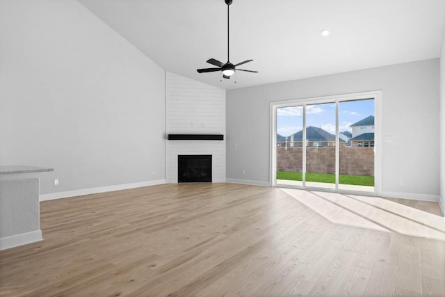 17224 Autumn Falls Dr, Manor, TX 78653 - unfurnished living room featuring light wood-style floors, a ceiling fan, a large fireplace, baseboards, and high vaulted ceiling