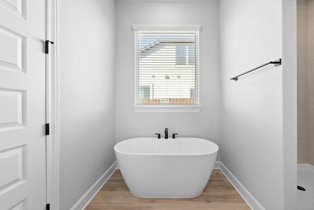 17224 Autumn Falls Dr, Manor, TX 78653 - bathroom with baseboards, wood finished floors, and a freestanding tub