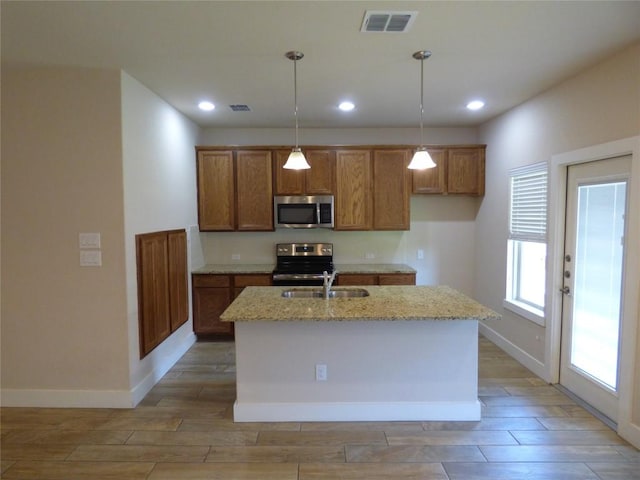 918 Crystal Brook Cv, New Braunfels, TX 78130 - kitchen featuring stainless steel appliances, a sink, wood tiled floors, brown cabinetry, and light stone countertops