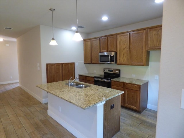 918 Crystal Brook Cv, New Braunfels, TX 78130 - kitchen featuring stainless steel appliances, a sink, light wood-type flooring, brown cabinets, and light stone countertops