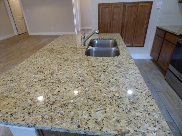 918 Crystal Brook Cv, New Braunfels, TX 78130 - kitchen featuring a sink, light stone counters, baseboards, and a kitchen island with sink