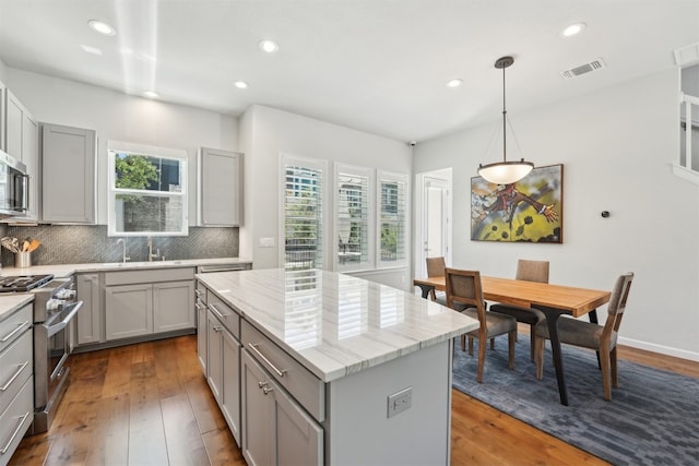 kitchen featuring gray cabinetry, stainless steel appliances, tasteful backsplash, a center island, and recessed lighting