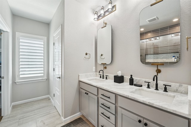 bathroom featuring baseboards, double vanity, and wood finished floors