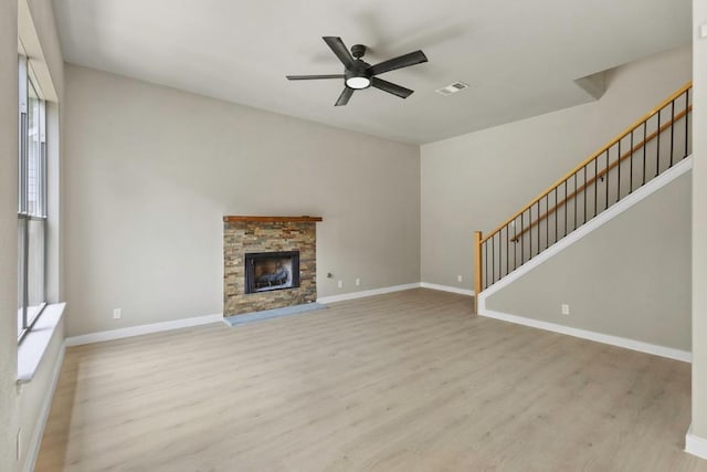 7057 Thistle Hill Way, Austin, TX 78754 - unfurnished living room featuring light wood-type flooring, ceiling fan, baseboards, a fireplace, and stairs