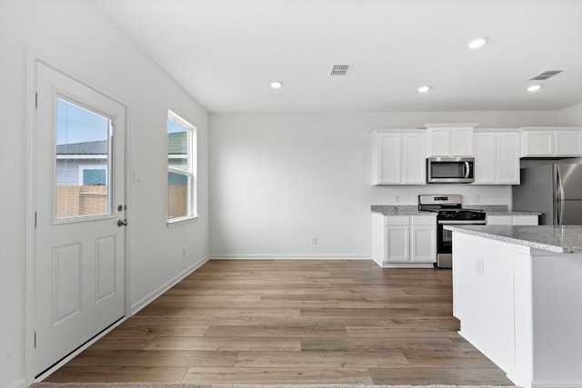 508 Aplite Pass, Maxwell, TX 78656 - kitchen featuring appliances with stainless steel finishes, white cabinetry, light wood-type flooring, recessed lighting, and light stone counters