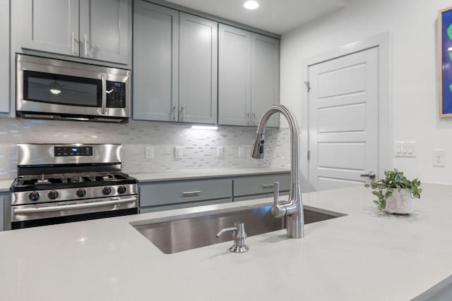 7301 Providence Ave Unit B, Austin, TX 78752 - kitchen with appliances with stainless steel finishes, gray cabinets, decorative backsplash, a sink, and recessed lighting