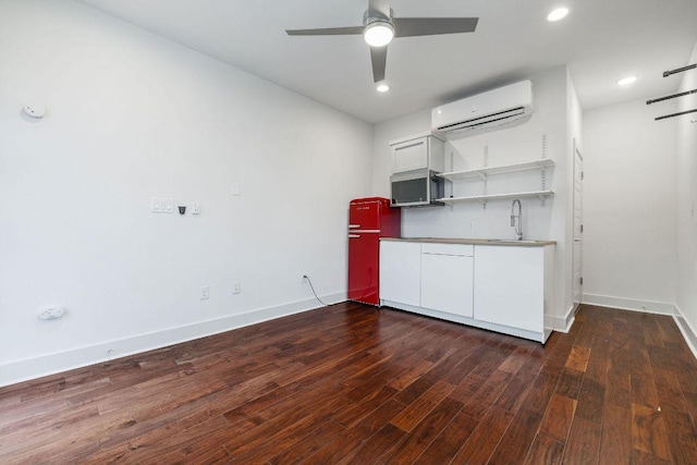 7301 Providence Ave Unit B, Austin, TX 78752 - kitchen with an AC wall unit, stainless steel microwave, dark wood-style flooring, a ceiling fan, and baseboards