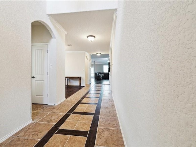 362 Maple Way, New Braunfels, TX 78132 - hallway with a textured wall, baseboards, arched walkways, inlaid floor details, and crown molding