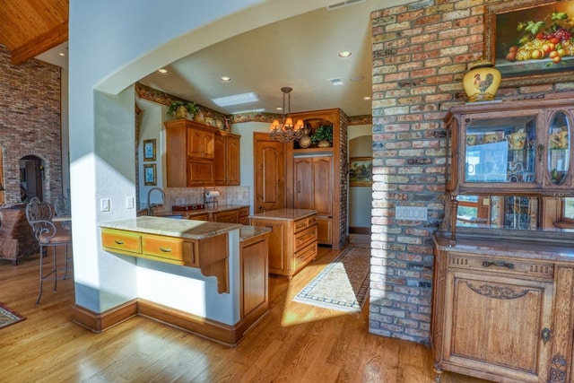 530 Scenic View Dr, Marble Falls, TX 78654 - kitchen featuring light wood-type flooring, arched walkways, a chandelier, and brown cabinets