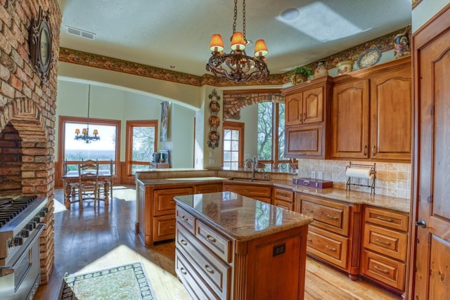 530 Scenic View Dr, Marble Falls, TX 78654 - kitchen with a chandelier, high end stove, a sink, brown cabinetry, and a textured ceiling