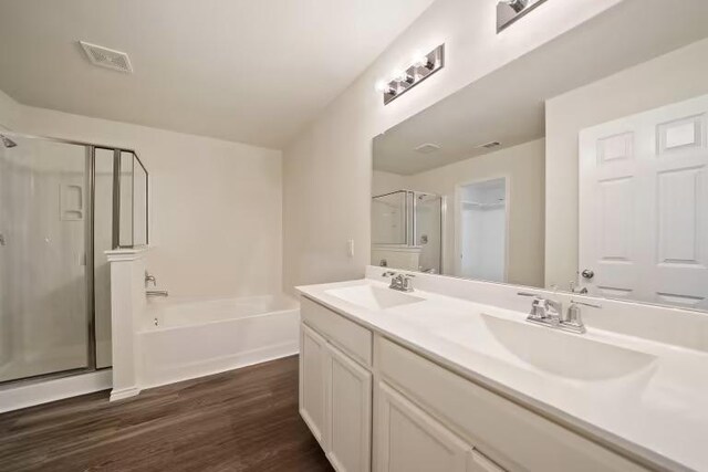 576 Tailwind Dr, Kyle, TX 78640 - bathroom featuring a stall shower, a garden tub, wood finished floors, and double vanity
