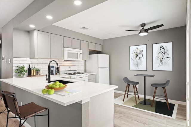 8330 Fathom Cir Unit 404, Austin, TX 78750 - kitchen with white appliances, a sink, light countertops, backsplash, and light wood-style floors