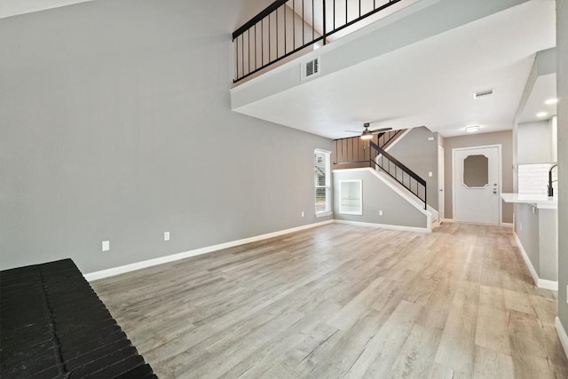8330 Fathom Cir Unit 404, Austin, TX 78750 - unfurnished living room with ceiling fan, light wood-style flooring, stairway, and a towering ceiling