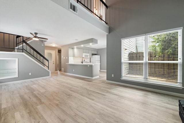 8330 Fathom Cir Unit 404, Austin, TX 78750 - unfurnished living room with stairway, light wood finished floors, ceiling fan, baseboards, and a sink