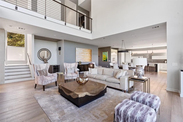 2551 Waymaker Way, Austin, TX 78746 - living area with light wood-style flooring, a high ceiling, and stairs