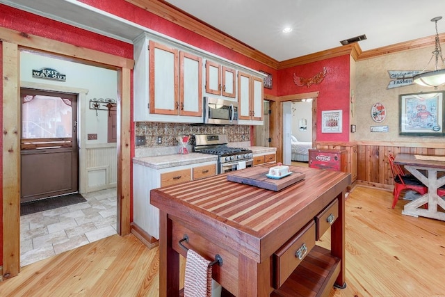 1110 County Road 487, Taylor, TX 76574 - kitchen featuring stainless steel appliances, light wood-style flooring, wainscoting, crown molding, and decorative light fixtures