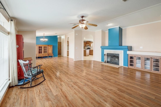 1110 County Road 487, Taylor, TX 76574 - unfurnished living room with ornamental molding, a ceiling fan, a chandelier, wood finished floors, and arched walkways