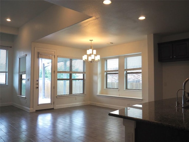 1902 Aves Cv, Pflugerville, TX 78660 - unfurnished dining area featuring a chandelier, baseboards, recessed lighting, a sink, and dark wood-style floors