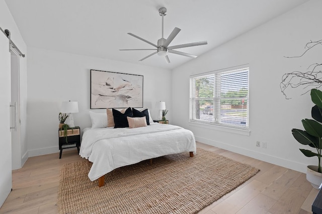 10300 Mourning Dove Dr, Austin, TX 78750 - bedroom featuring a barn door, lofted ceiling, light wood finished floors, baseboards, and a ceiling fan