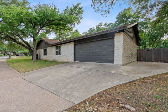 10300 Mourning Dove Dr, Austin, TX 78750 - view of side of property featuring an attached garage, driveway, and stone siding