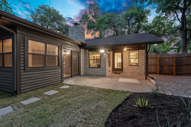 10300 Mourning Dove Dr, Austin, TX 78750 - back of house at dusk with a chimney, a patio, and stone siding