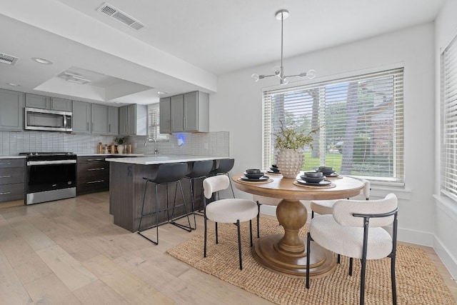10300 Mourning Dove Dr, Austin, TX 78750 - kitchen with appliances with stainless steel finishes, gray cabinets, light countertops, backsplash, and light wood-style flooring