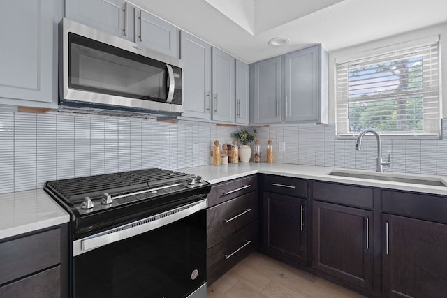 10300 Mourning Dove Dr, Austin, TX 78750 - kitchen featuring gas range oven, stainless steel microwave, a sink, light countertops, and decorative backsplash