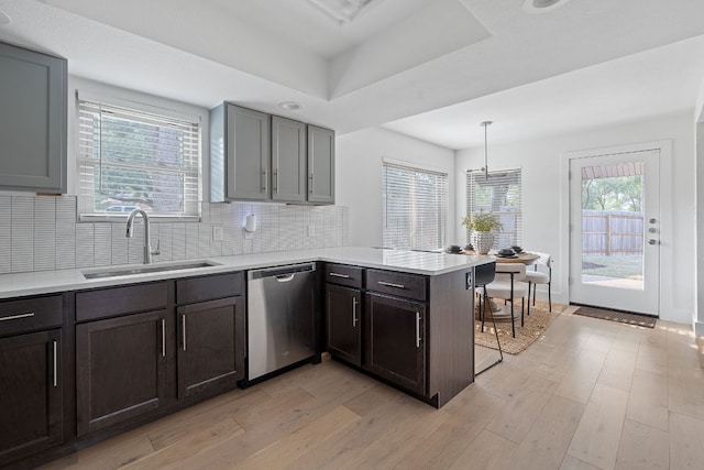 10300 Mourning Dove Dr, Austin, TX 78750 - kitchen featuring stainless steel dishwasher, a sink, a peninsula, light wood-style floors, and light countertops