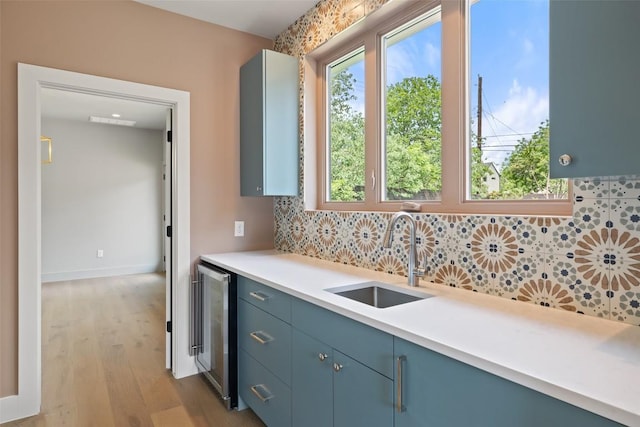 4600 Parkdale Pl, Austin, TX 78745 - kitchen featuring a sink, beverage cooler, tasteful backsplash, light wood-type flooring, and light countertops