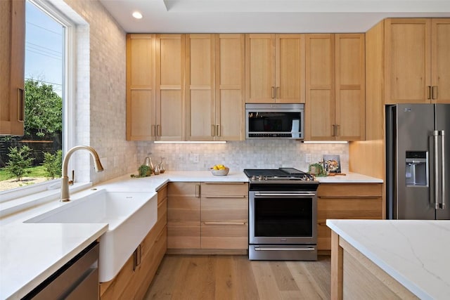 4600 Parkdale Pl, Austin, TX 78745 - kitchen featuring stainless steel appliances, light brown cabinetry, light wood finished floors, tasteful backsplash, and recessed lighting