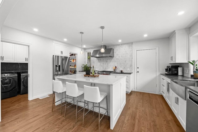 4107 Jefferson St, Austin, TX 78731 - kitchen with appliances with stainless steel finishes, extractor fan, washer and dryer, white cabinetry, and recessed lighting