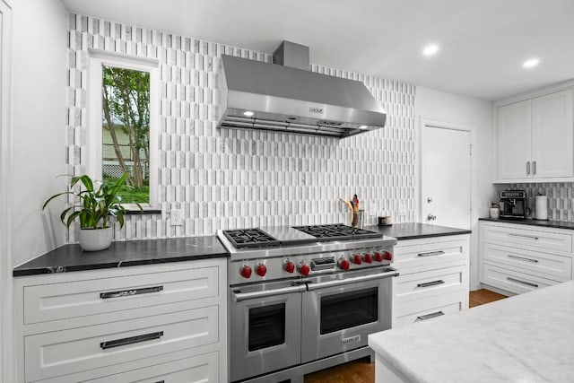 4107 Jefferson St, Austin, TX 78731 - kitchen with range with two ovens, wall chimney exhaust hood, tasteful backsplash, white cabinets, and recessed lighting