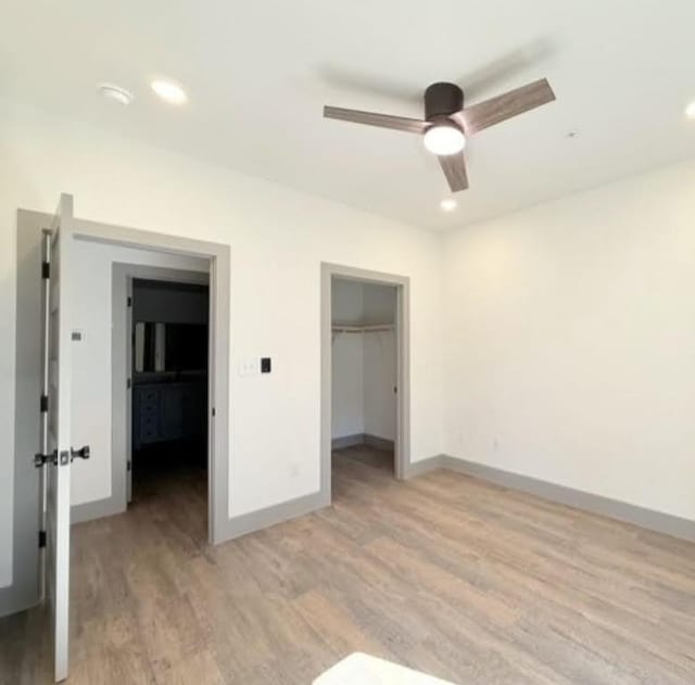 2450 Wickersham Ln Unit 1926, Austin, TX 78741 - unfurnished bedroom featuring light wood finished floors, baseboards, recessed lighting, and a walk in closet