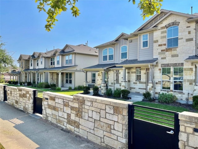513 N Heatherwilde Blvd, Pflugerville, TX 78660 - townhome / multi-family property with a gate, a residential view, a fenced front yard, and stone siding