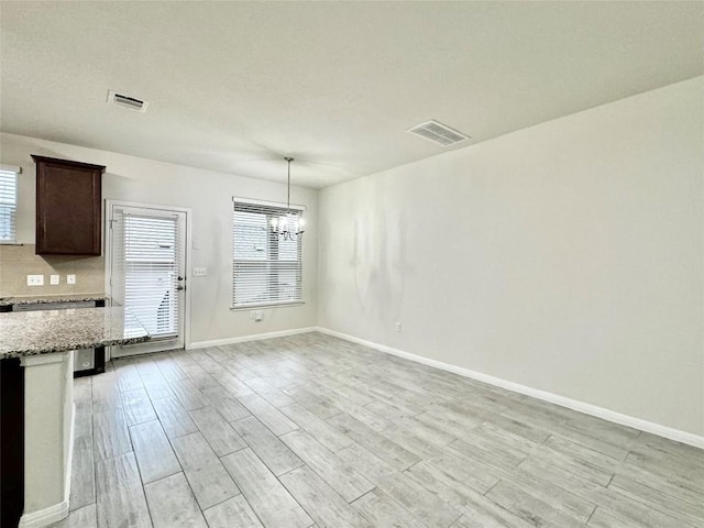 513 N Heatherwilde Blvd, Pflugerville, TX 78660 - unfurnished dining area featuring a chandelier, light wood-style flooring, and baseboards