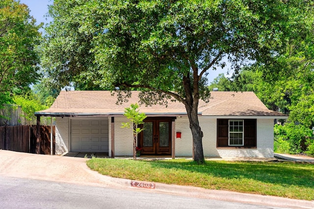 2403 Little John Ln, Austin, TX 78704 - ranch-style house featuring an attached garage, brick siding, driveway, and french doors