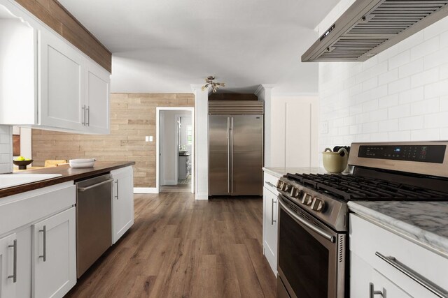 2403 Little John Ln, Austin, TX 78704 - kitchen with stainless steel appliances, range hood, decorative backsplash, white cabinetry, and dark wood-type flooring