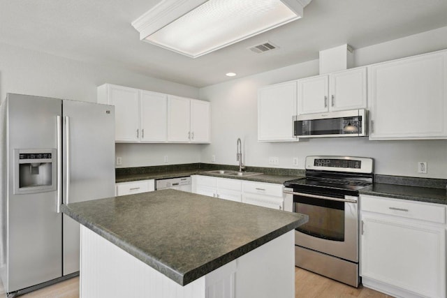 100 Blanco Woods Blvd, Elgin, TX 78621 - kitchen featuring stainless steel appliances, a sink, white cabinetry, light wood-style floors, and dark countertops