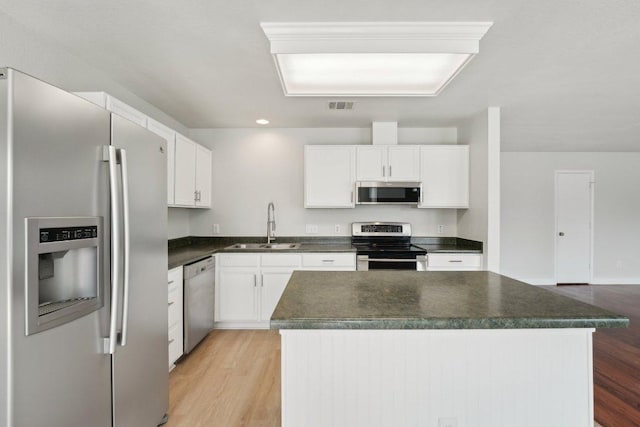 100 Blanco Woods Blvd, Elgin, TX 78621 - kitchen with appliances with stainless steel finishes, a sink, dark countertops, light wood-type flooring, and white cabinetry