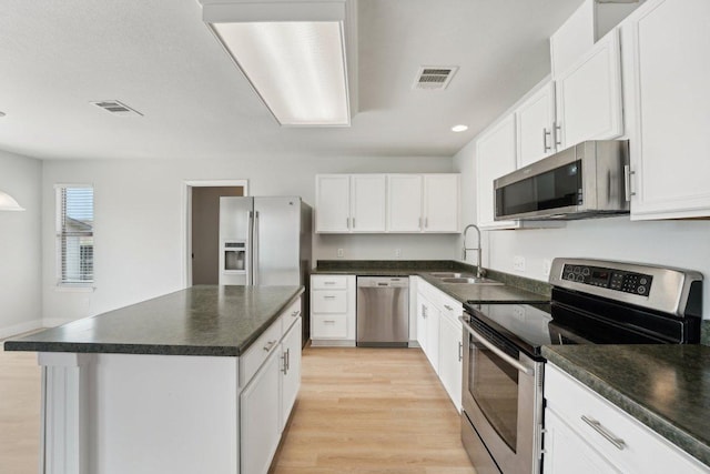 100 Blanco Woods Blvd, Elgin, TX 78621 - kitchen featuring stainless steel appliances, a sink, dark countertops, light wood-type flooring, and white cabinetry