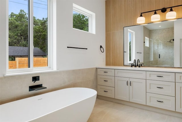402 Fife Dr, Spicewood, TX 78669 - bathroom with a shower stall, a freestanding bath, vanity, tile patterned flooring, and tile walls
