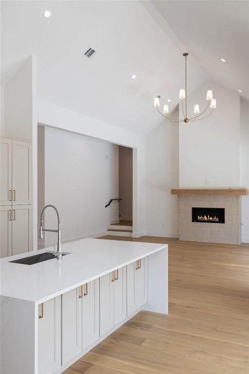 402 Fife Dr, Spicewood, TX 78669 - kitchen with a sink, lofted ceiling, light wood finished floors, a chandelier, and decorative light fixtures