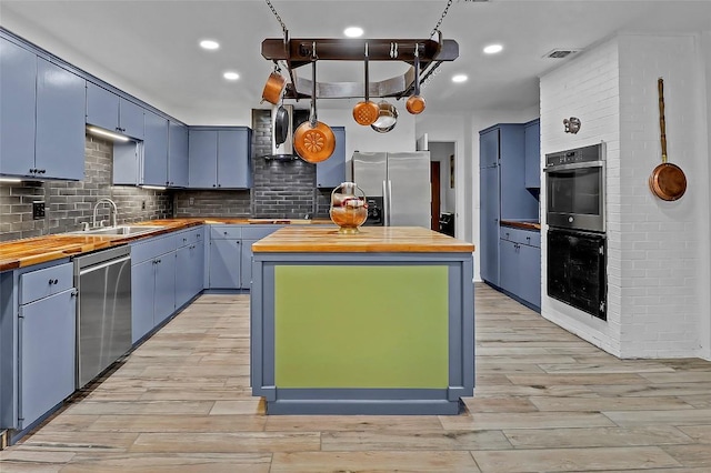 122 W Sierra Cir, San Marcos, TX 78666 - kitchen with wood counters, appliances with stainless steel finishes, a sink, blue cabinetry, and recessed lighting
