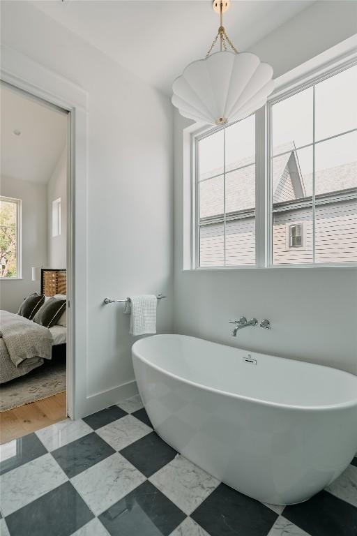 113 Nelray Blvd Unit 1, Austin, TX 78751 - ensuite bathroom featuring a soaking tub, baseboards, and a chandelier
